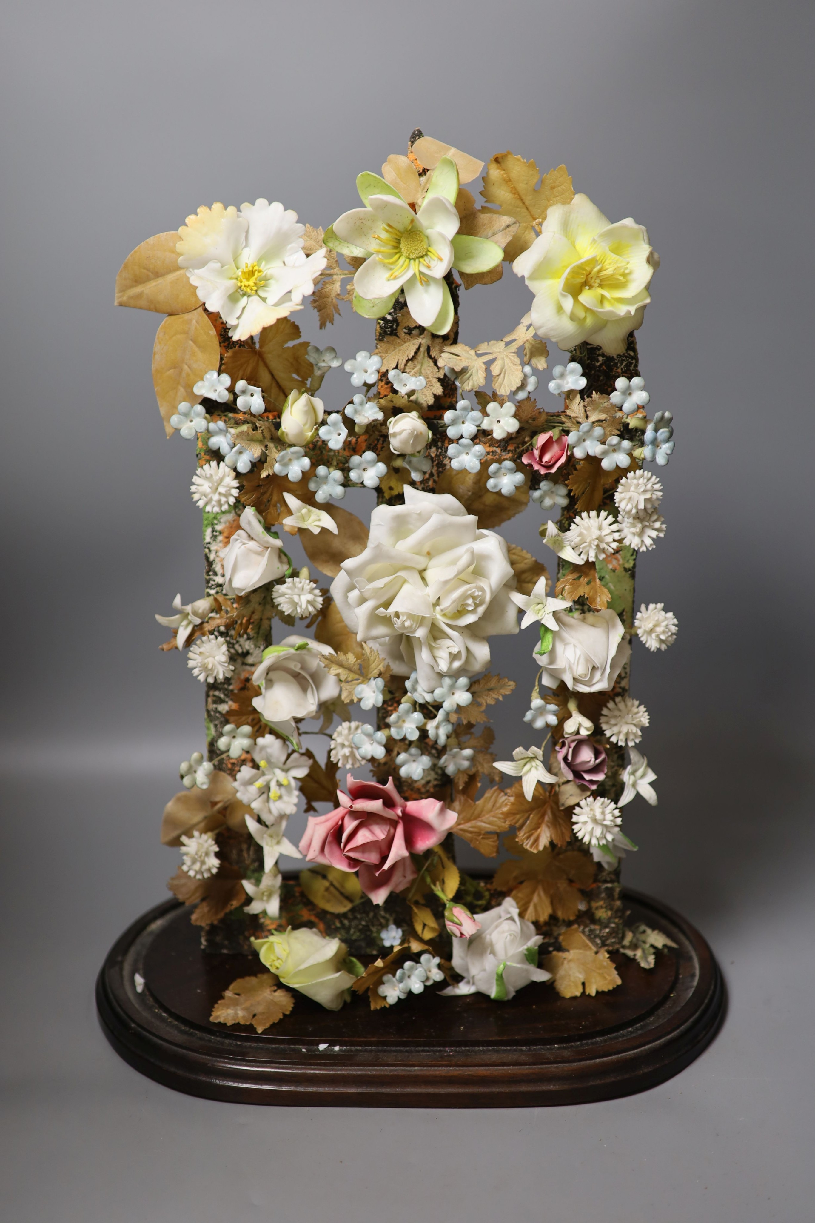 A late 19th century model of porcelain flowers under a glass dome 52cm total height